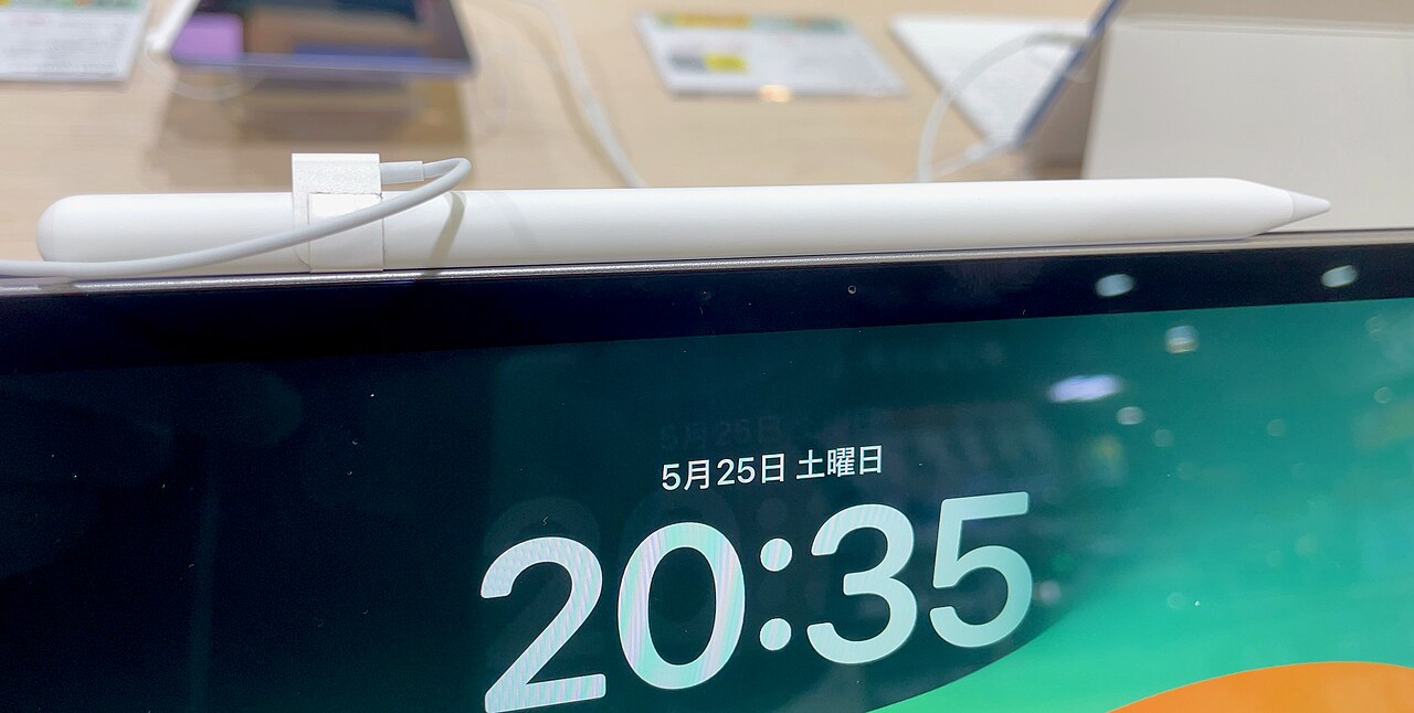 Apple Pencil resting on an iPad screen showing the lock screen clock