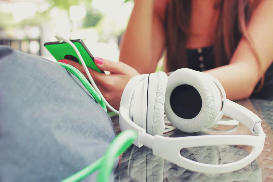 Person listening to music through headphones while checking a smartphone