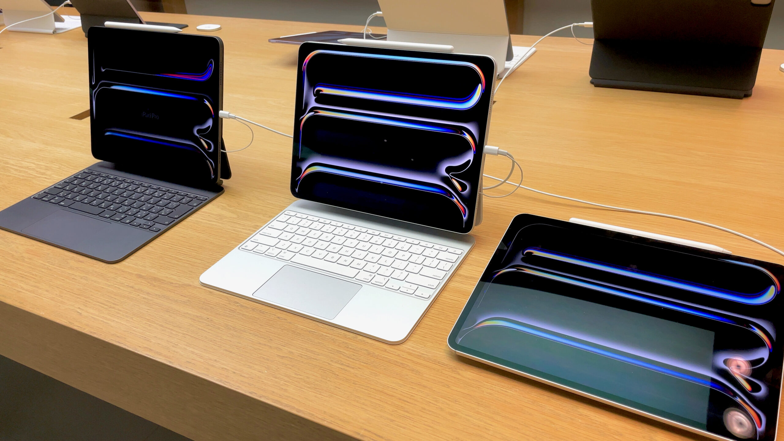 Apple iPad Pro models with OLED screens showing deep blacks and vivid color on display in a store