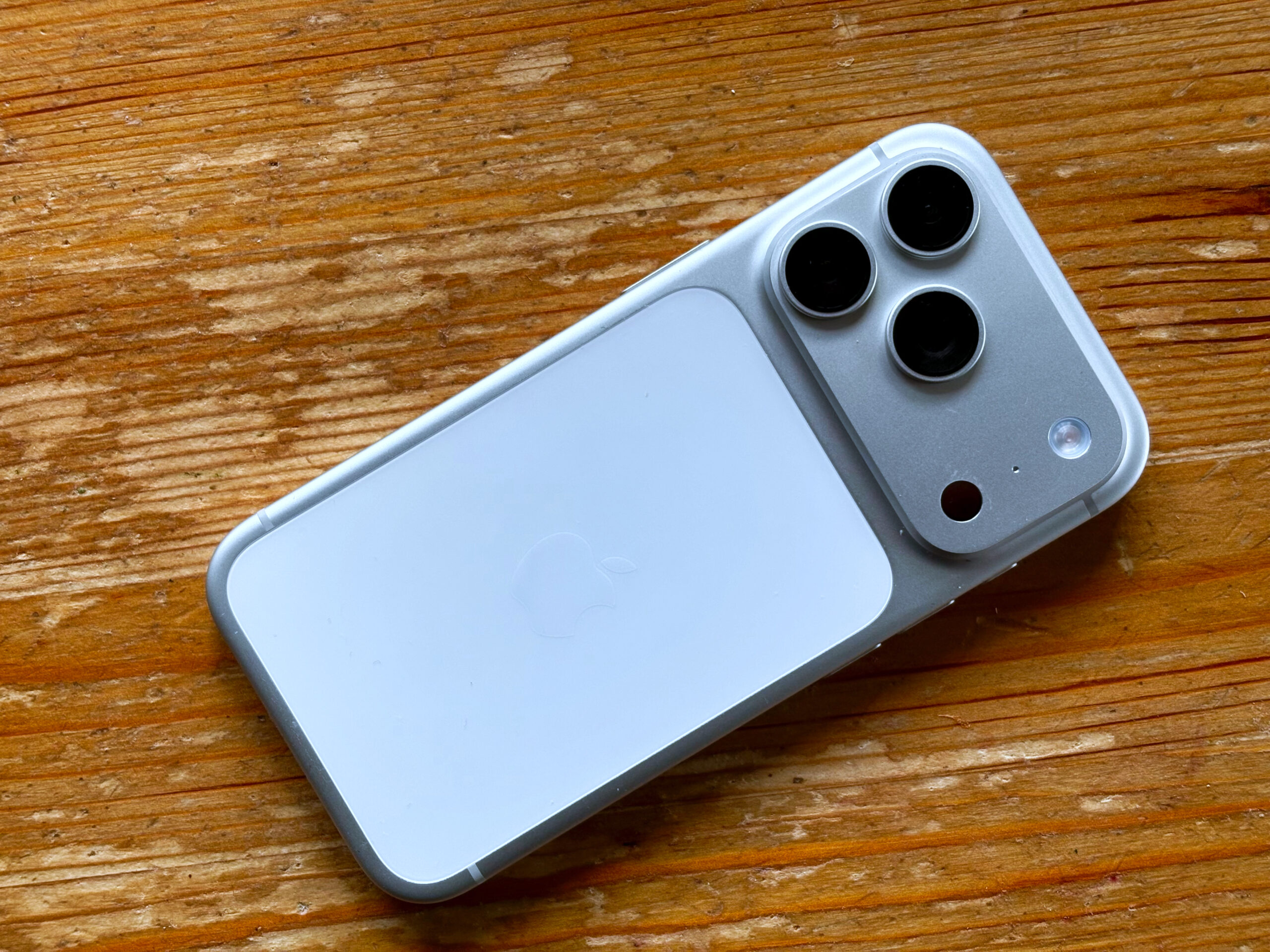 Close-up of a modern iPhone camera module on a wooden table