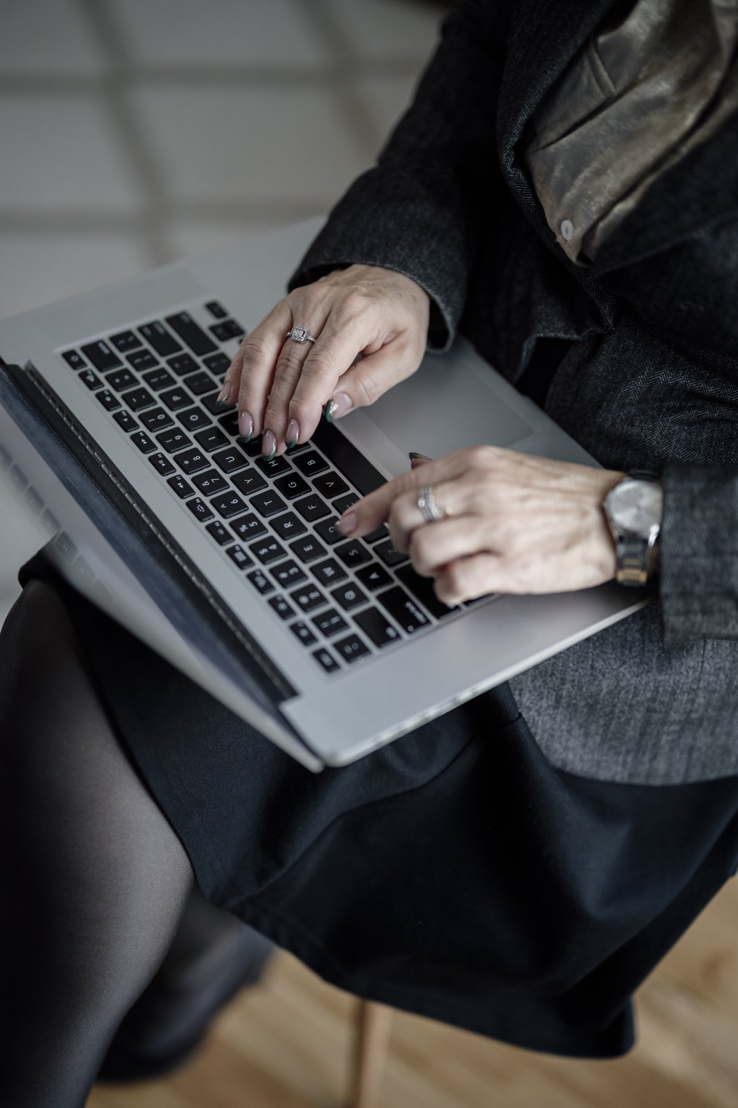 Close-up of hands typing on a laptop keyboard in an office