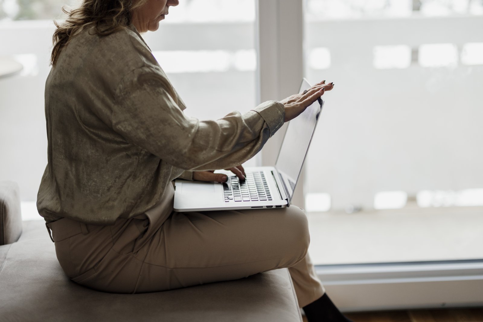 Woman using a laptop on battery power while sitting by a window