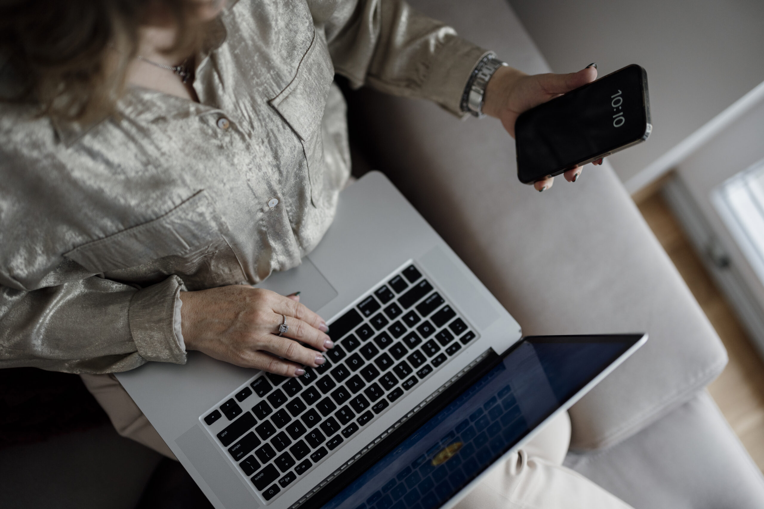 Person checking an iPhone while working on a laptop